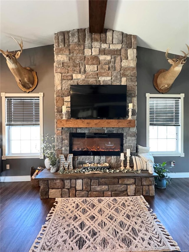 living area featuring vaulted ceiling with beams, a fireplace, baseboards, and wood finished floors