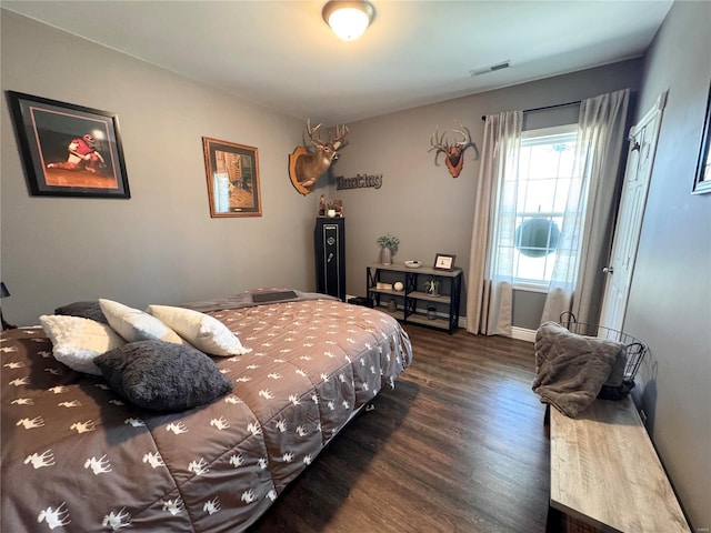 bedroom with visible vents, baseboards, and wood finished floors