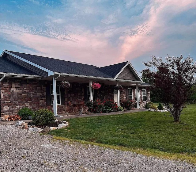 single story home featuring stone siding, a porch, and a front yard