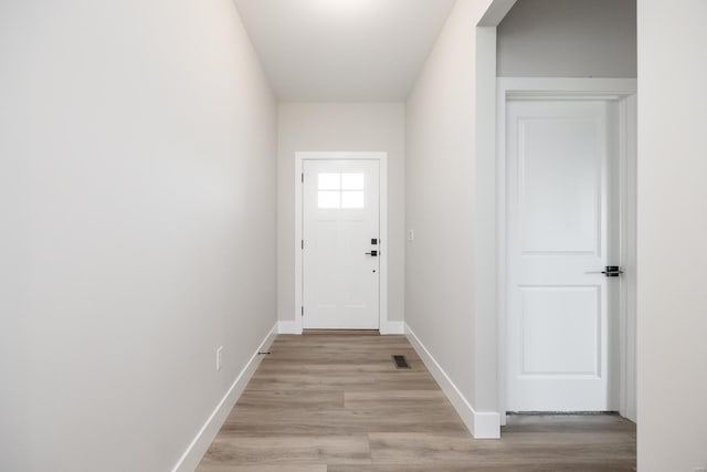 doorway with light wood-type flooring, visible vents, and baseboards