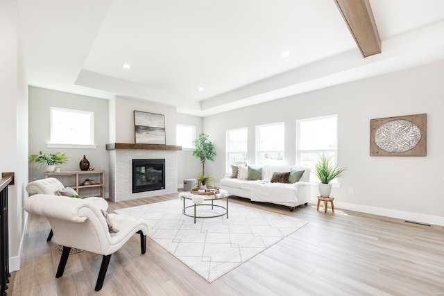 living room with recessed lighting, visible vents, light wood-style flooring, a glass covered fireplace, and baseboards