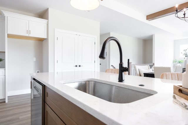 kitchen with light wood-style flooring, a sink, white cabinetry, dishwasher, and beamed ceiling