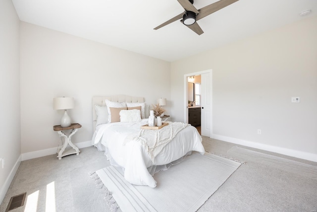 bedroom with light carpet, visible vents, baseboards, a ceiling fan, and ensuite bathroom