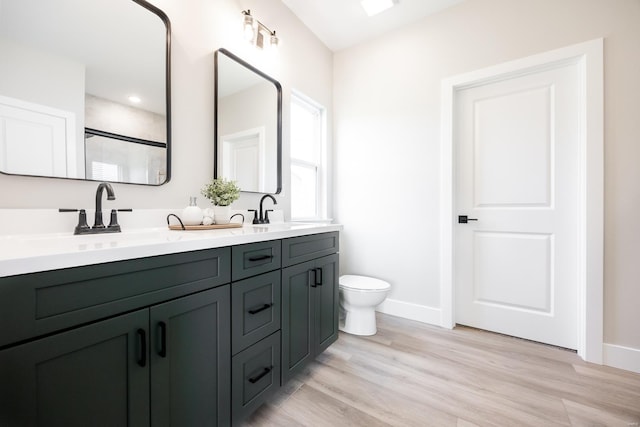 full bath featuring double vanity, toilet, a sink, and wood finished floors