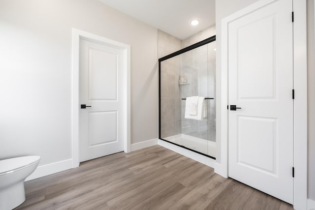 full bath with toilet, a shower stall, baseboards, and wood finished floors