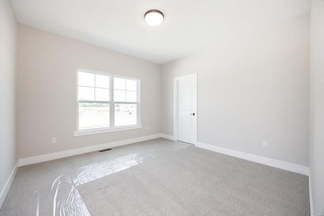 carpeted spare room with visible vents and baseboards