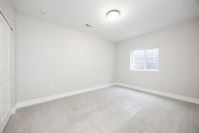 empty room featuring light carpet, visible vents, and baseboards