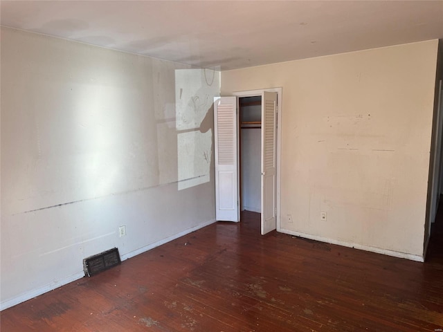 spare room with baseboards and wood finished floors