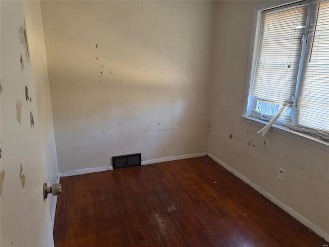 empty room featuring baseboards, visible vents, and hardwood / wood-style floors