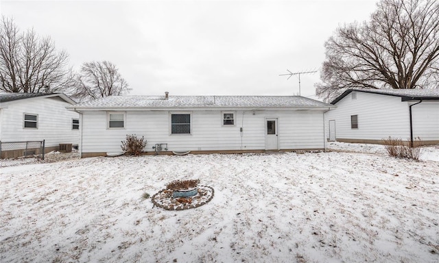 snow covered house with fence and central AC unit