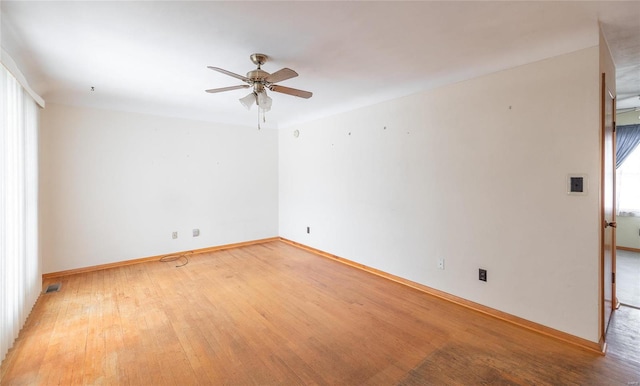 spare room featuring light wood-style floors, baseboards, and a ceiling fan