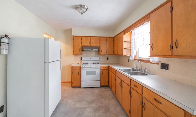 kitchen featuring white appliances, tasteful backsplash, under cabinet range hood, and a sink