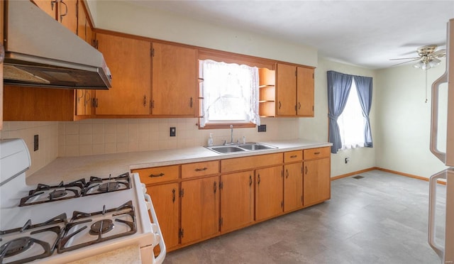 kitchen with a sink, under cabinet range hood, light countertops, and gas range gas stove