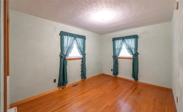 unfurnished room featuring a textured ceiling, hardwood / wood-style flooring, and visible vents