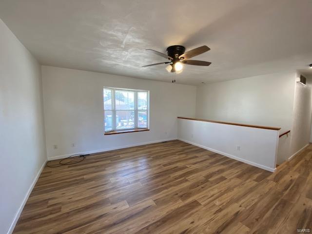 empty room featuring a ceiling fan, baseboards, and wood finished floors