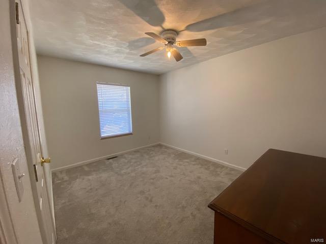 carpeted spare room with ceiling fan and baseboards