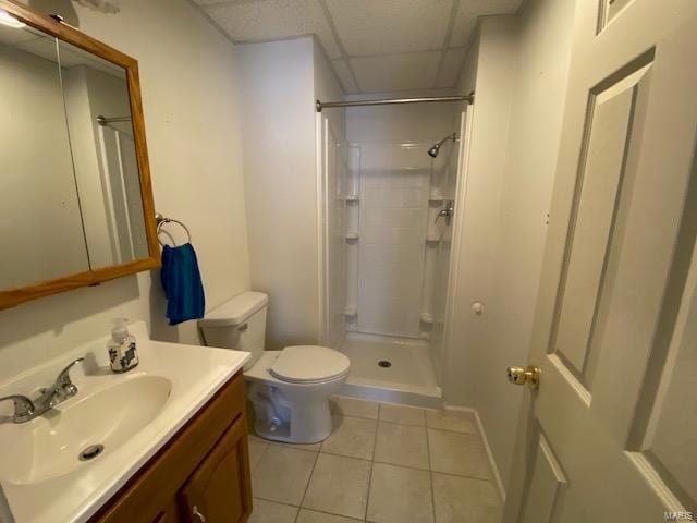 bathroom featuring a drop ceiling, tile patterned flooring, toilet, vanity, and walk in shower