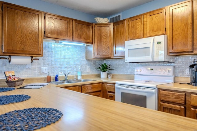 kitchen featuring white appliances, tasteful backsplash, light countertops, and a sink