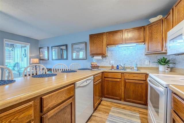 kitchen featuring brown cabinets, white appliances, light countertops, and a sink