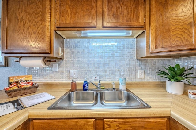 kitchen featuring brown cabinetry, backsplash, and a sink