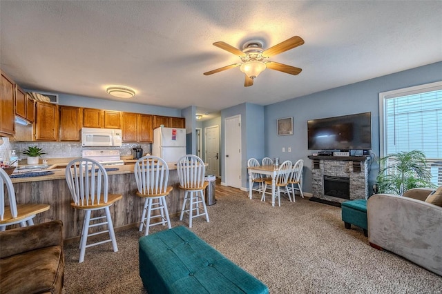 kitchen with a peninsula, white appliances, backsplash, and light countertops