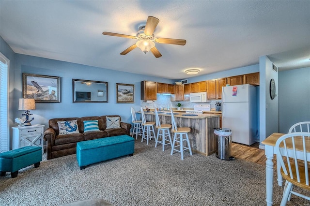 carpeted living area with visible vents and a ceiling fan