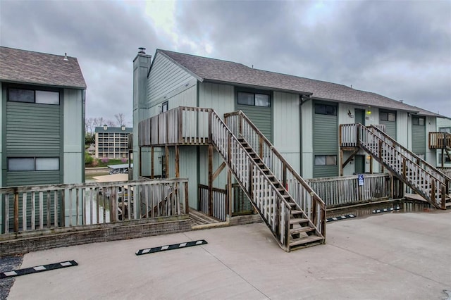 back of house featuring a patio area, a shingled roof, and stairway