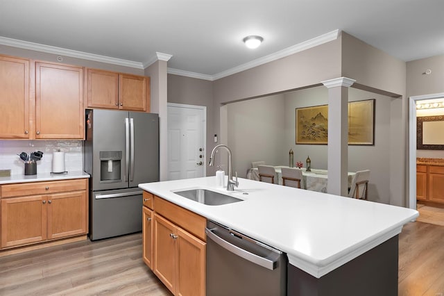 kitchen with appliances with stainless steel finishes, light countertops, a sink, and light wood finished floors