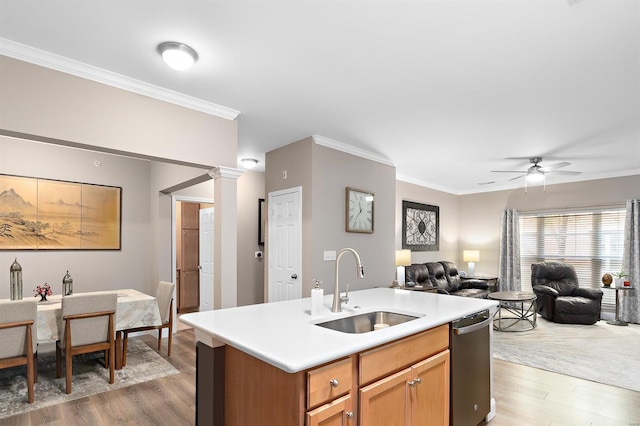 kitchen featuring ornate columns, ornamental molding, open floor plan, and a sink