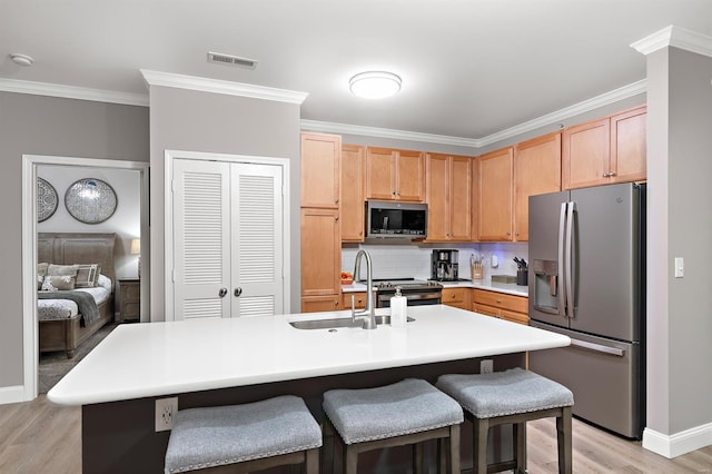 kitchen featuring light wood-style flooring, a sink, visible vents, appliances with stainless steel finishes, and crown molding