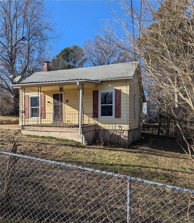 bungalow-style house with covered porch, fence, a chimney, and crawl space