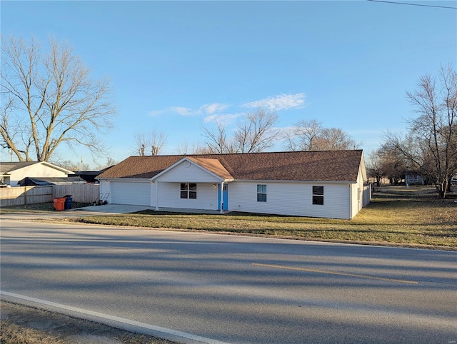 view of front of property featuring a front lawn, an attached garage, fence, and driveway