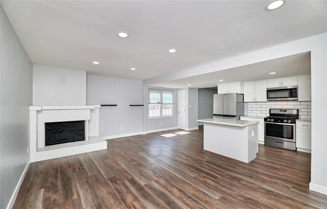 kitchen featuring decorative backsplash, dark wood finished floors, a kitchen island, open floor plan, and stainless steel appliances