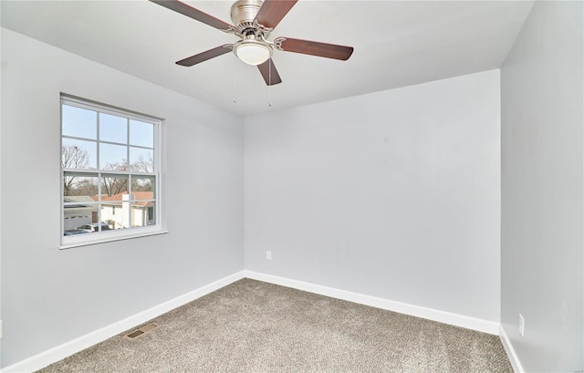 spare room featuring carpet floors, a ceiling fan, visible vents, and baseboards