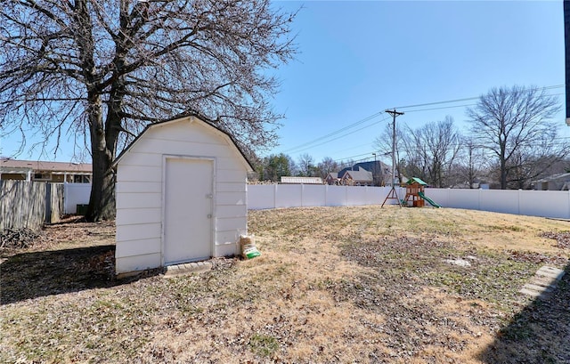 view of yard featuring a playground, a storage unit, an outdoor structure, and a fenced backyard