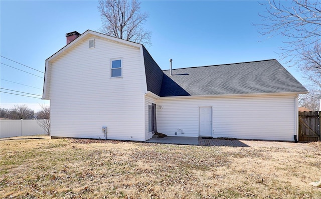 back of house with a patio, a chimney, roof with shingles, fence, and a yard