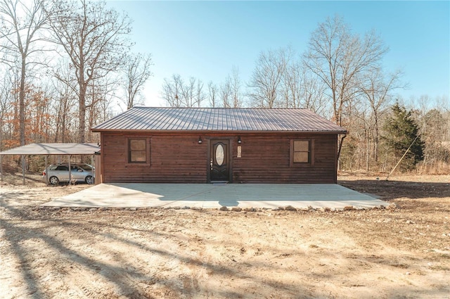 rear view of house with a carport, driveway, and metal roof