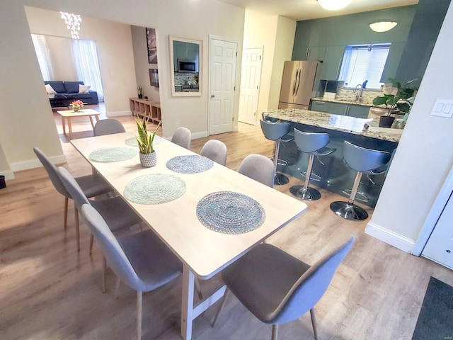 dining space with light wood-type flooring and baseboards