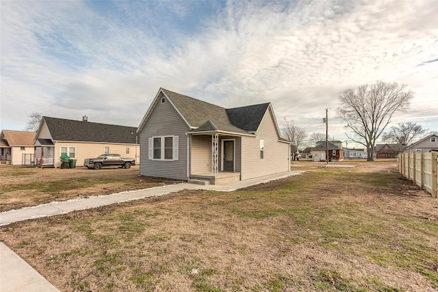 bungalow featuring fence and a front lawn