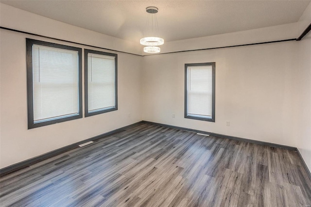 unfurnished room with wood finished floors, visible vents, and baseboards