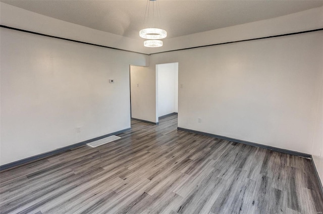 empty room with visible vents, baseboards, and wood finished floors