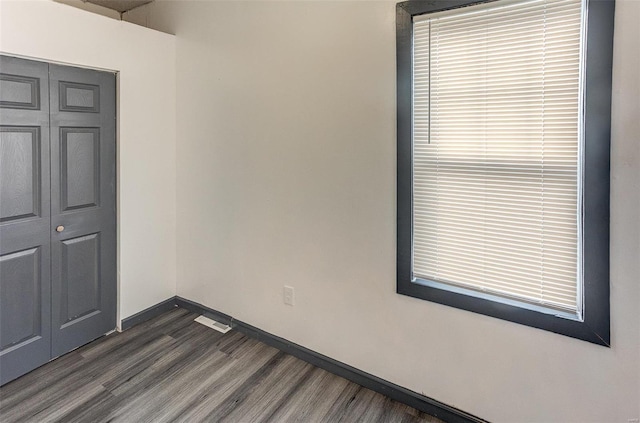 unfurnished room with dark wood-style flooring and baseboards