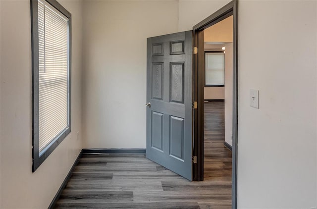 corridor featuring baseboards and wood finished floors