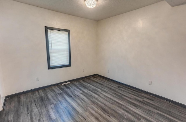 unfurnished room with dark wood-type flooring and baseboards