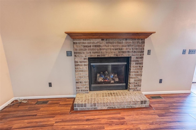 room details featuring a brick fireplace, wood finished floors, and baseboards