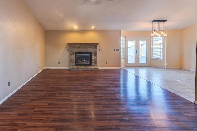 unfurnished living room with baseboards, dark wood-type flooring, french doors, a fireplace, and recessed lighting