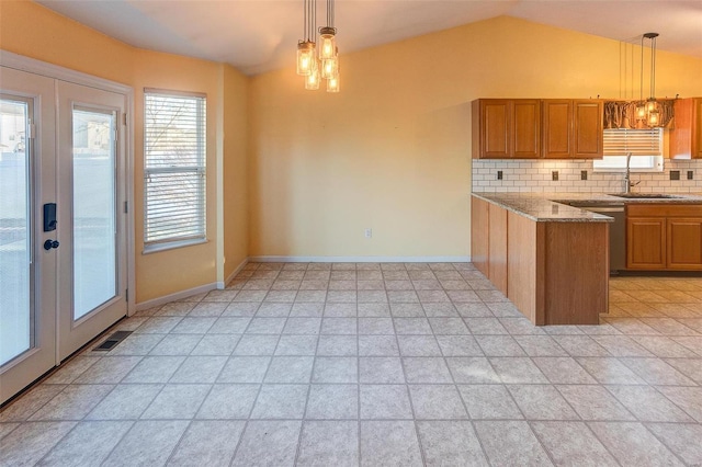 kitchen with tasteful backsplash, an inviting chandelier, brown cabinetry, a sink, and dishwasher