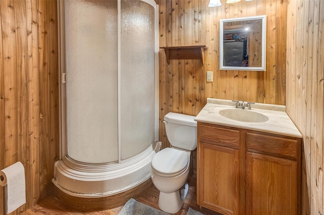 bathroom featuring a stall shower, wood walls, vanity, and toilet