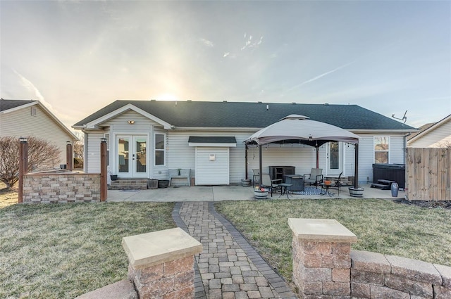 rear view of property with a hot tub, a lawn, french doors, a gazebo, and a patio area