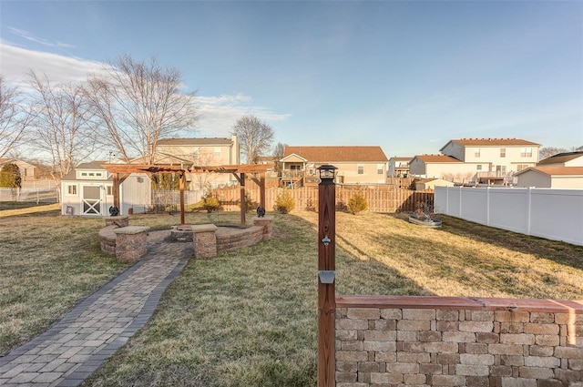 view of yard with a storage unit, an outdoor fire pit, a residential view, a fenced backyard, and an outdoor structure